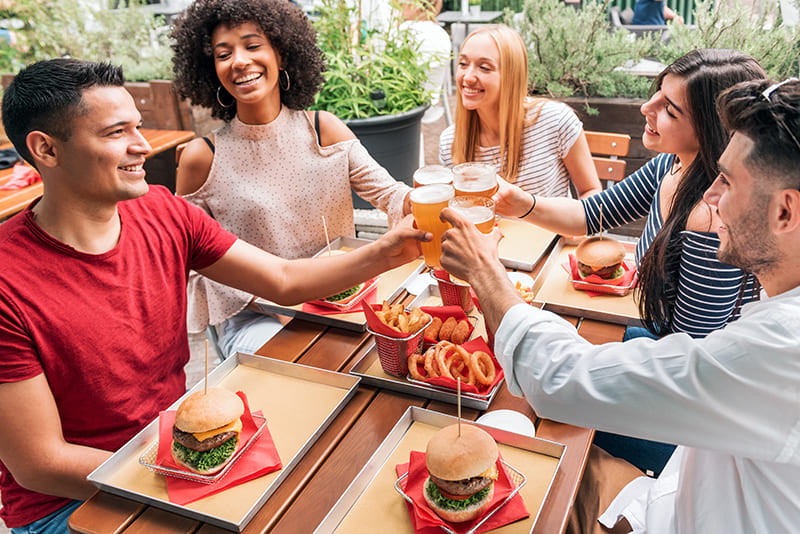 amigos brindando con cerveza y comiendo hamburguesas juntos