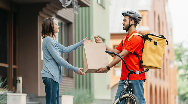 repartidor entrega un paquete a una mujer delivery